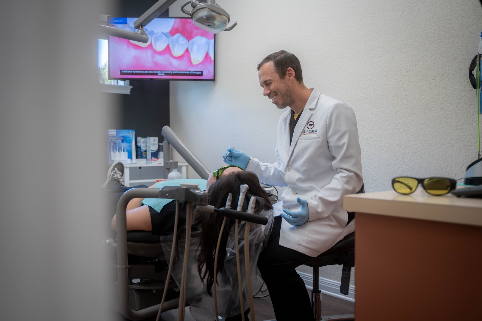 Dr. Grant Glauser speaking with a patient reclined in a treatment chair inside Glauser Family Dentistry