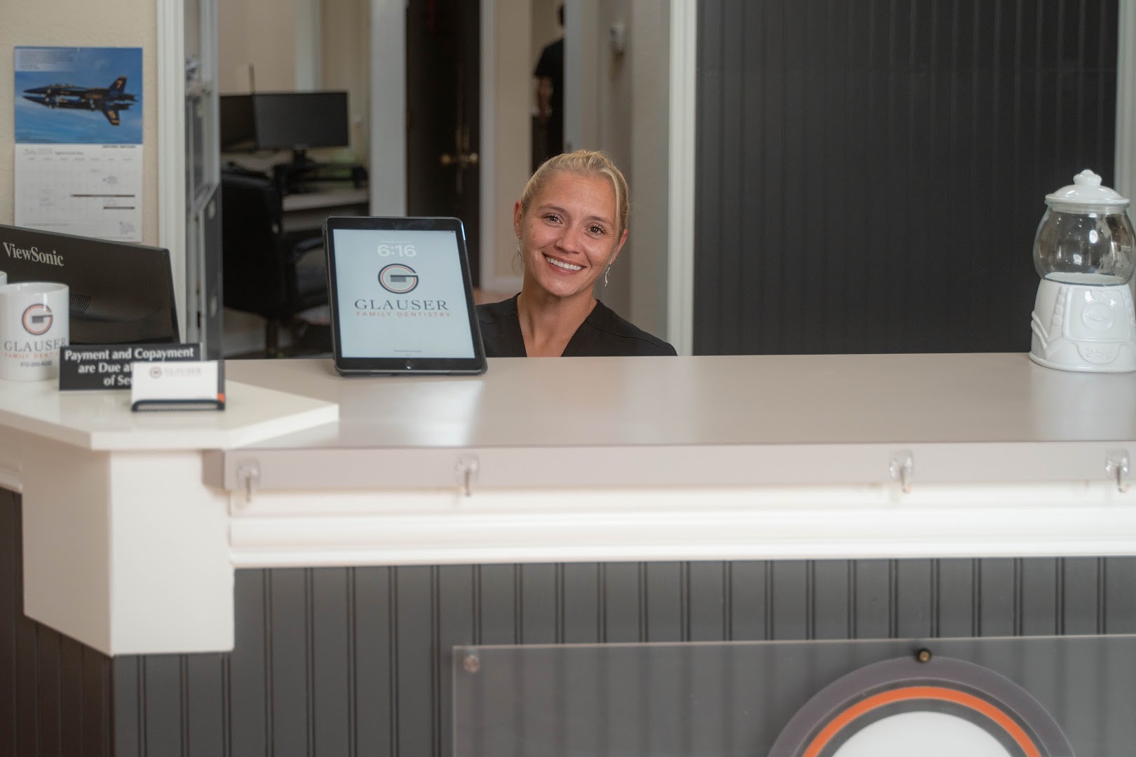 Friendly team member smiling behind the front desk at Glauser Family Dentistry